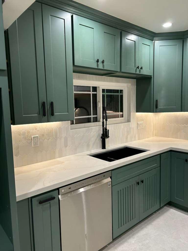 Sink run with a black composite sink, matte black pull-down faucet, dishwasher and a window framed into the backsplash