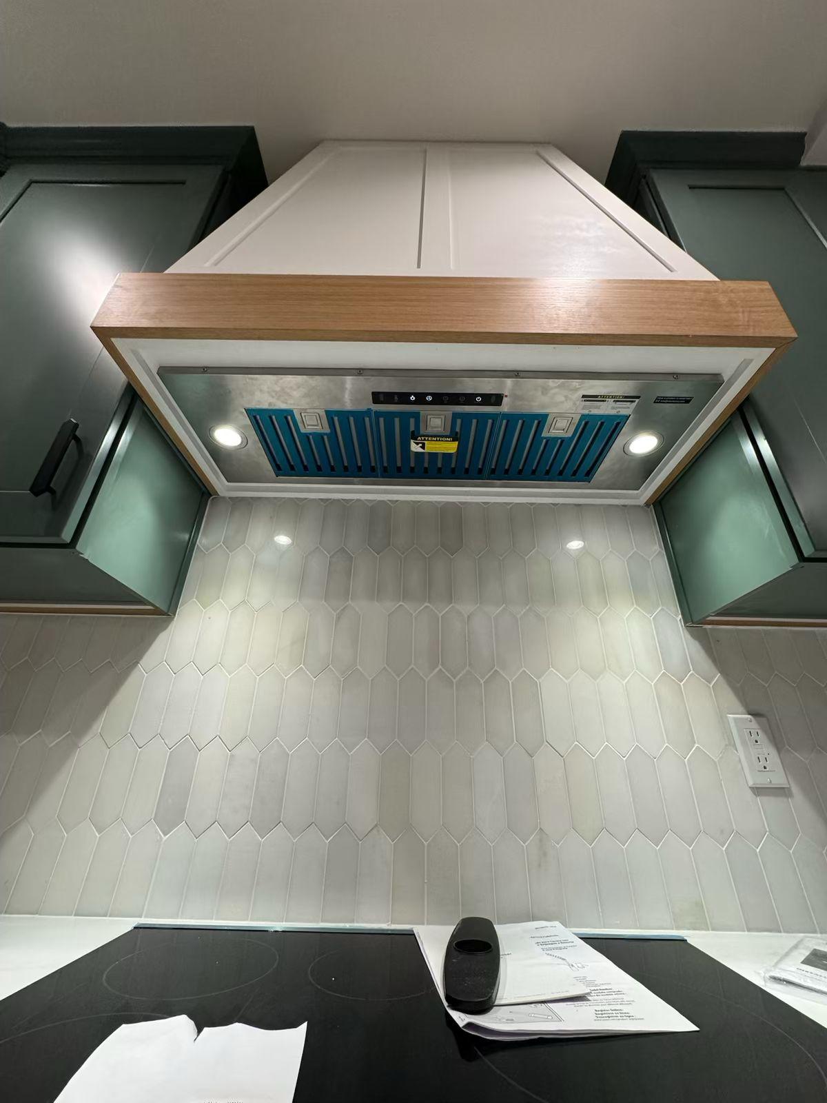 Underside of the hood insert with its integrated lighting, seen against the picket backsplash