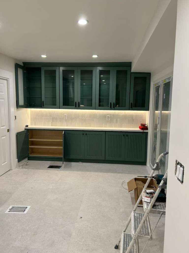 The pantry wall with glass-front upper cabinets, under-cabinet lighting and beadboard base cabinets